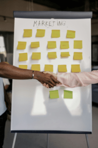 A broad with yellow sticky note two people shaking hand